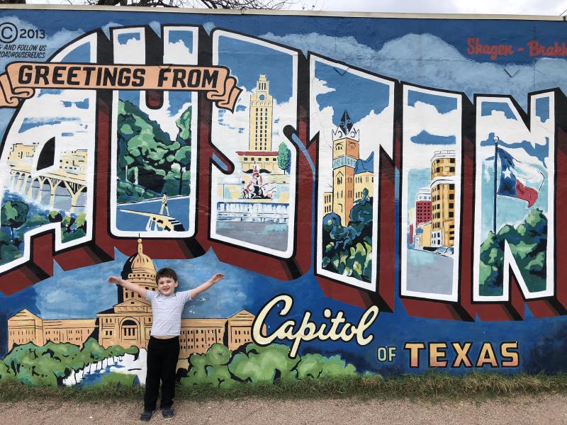 Max in front of the 'Greetings from Austin' sign
