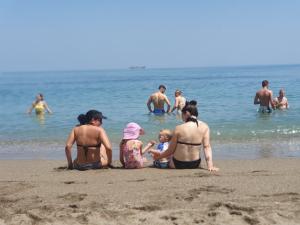 Esther shows Mark a shell while sitting on the beach with Tyren and Millie